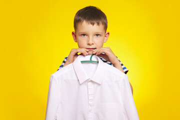 Boy Holding White Shirt on Hanger Against Yellow