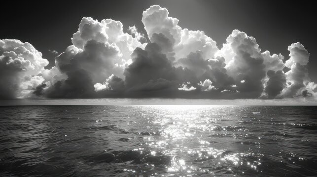 a black and white photo of the sun shining through clouds over a body of water with the ocean in the foreground.