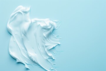 Creamy beauty product smudge swiped on light blue background