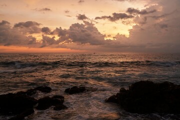 Mirissa, Sri Lanka. Golden sunset over ocean horizon, serene seascape with waves hitting rocks, warm dusk light reflects on water surface, tranquil sea at twilight, coastal evening ambiance.