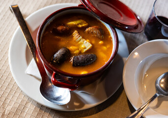 Asturian fabada soup with beans and pork served in bowl to table..