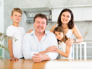 Portrait of happy family - father and mother with two children at the table at home