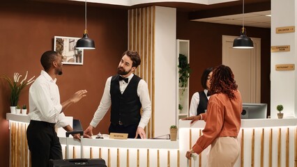 Helpful front desk receptionists answering customer inquiries about hotel facilities during guests...