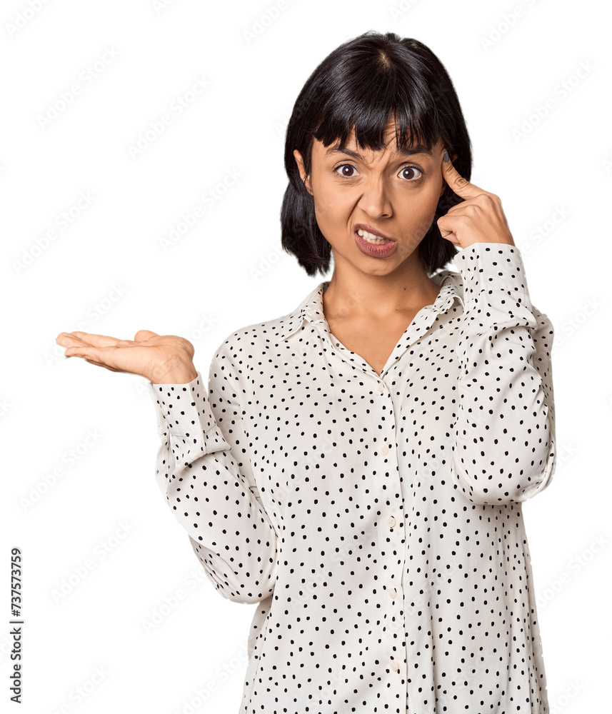 Poster young hispanic woman with short black hair in studio holding and showing a product on hand.