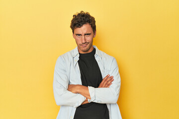Young Latino man posing on yellow background unhappy looking in camera with sarcastic expression.