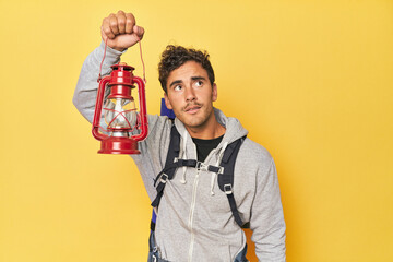 Traveler with mountain backpack and lantern on yellow.