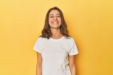 Obraz premium Middle-aged caucasian woman on yellow laughs and closes eyes, feels relaxed and happy.