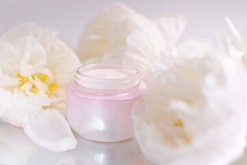 Obraz na płótnie Canvas Cream cosmetic jar mock up with flowers on background, skin care therapy