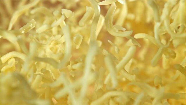 The grated cheese flies up and falls down. On an orange background. Filmed on a high-speed camera at 1000 fps. High quality FullHD footage