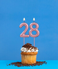 Birthday candle with cupcake on blue background - Number 28