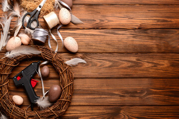 Composition with supplies for creating Easter wreath on brown wooden table