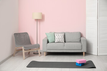 Interior of living room with sofa, chair and yoga equipment