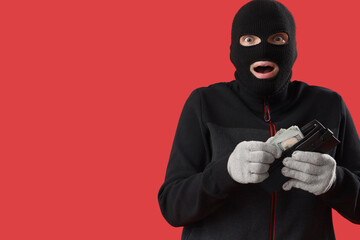 Shocked male burglar with wallet of money on red background