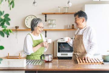 キッチンでコーヒーを作って味見するグルメなアジア人高齢者夫婦（笑顔）

