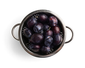 Colander with ripe plums on white background