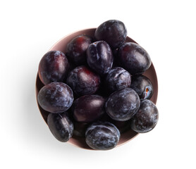 Bowl with ripe plums on white background