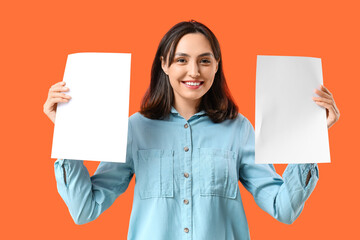 Young woman with blank paper sheets on orange background