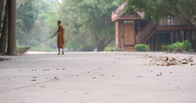 Monks are cleaning the temple area. Monks are sweeping the floor.,Thai temple