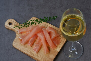 塩味が効いておいしい生ハムをおつまみに、辛口の白ワインを飲む
