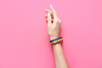 Woman with rainbow bracelet on pink background. LGBTQ concept - obrazy, fototapety, plakaty