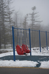 red swing in the snow in the park