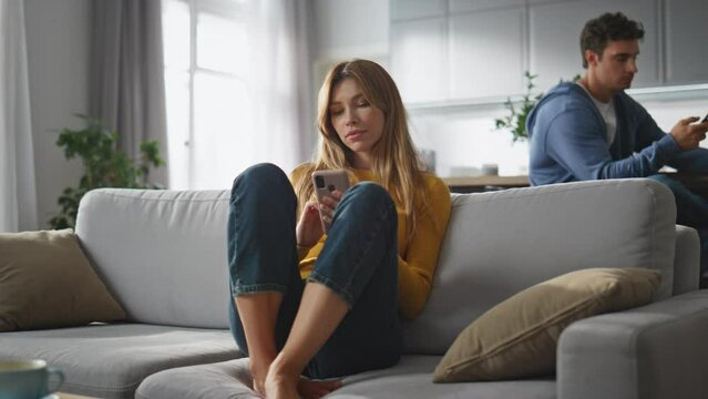 Internet addicted pair messaging smartphones at home. Woman scrolling cellphone
