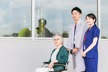 病院・介護施設にいる車椅子に乗った高齢者と医師・看護師
