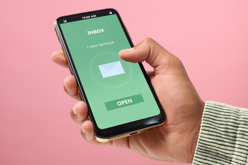Got new message. Man using smartphone on pink background, closeup