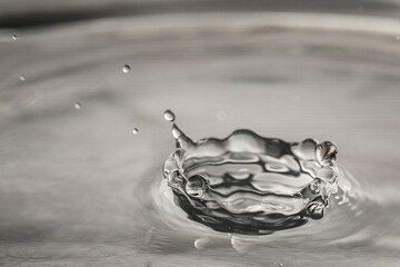 Splash of clear water with drops on grey background, closeup