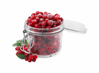 Frozen red cranberries in glass jar and green leaves isolated on white