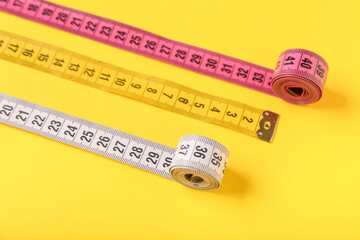 Different measuring tapes on yellow background