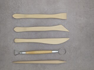 Wooden and metal sculpt tools on gray cement background, horizontal