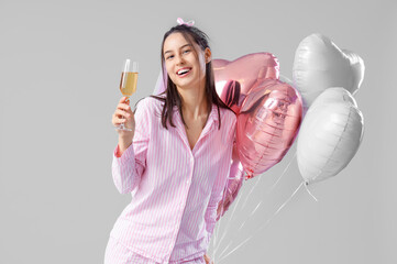 Happy bridesmaid in pajamas with champagne and balloons on light background. Hen Party - obrazy, fototapety, plakaty