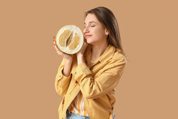 Young woman with half of pomelo on brown background
