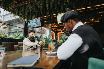Young entrepreneurs engaged in work at a contemporary urban coffee shop, showcasing modern work culture and collaboration in a casual setting.