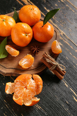 Board of sweet mandarins with cinnamon and star anise on black wooden background