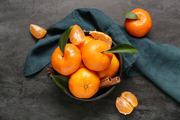 Bowl of sweet mandarins with cinnamon and star anise on black background