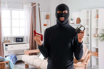 Male thief with hacksaw and broken lock in room - obrazy, fototapety, plakaty