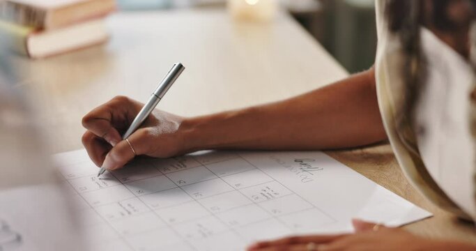 Hand, writing and calendar, plan schedule on desk and organization with timeline for tasks or event. Priority, agenda and goals with person for productivity, time management and reminder for deadline