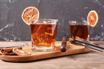 Board with glasses of delicious Old Fashioned Cocktail and orange slices on wooden table