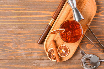 Board with glass of delicious Old Fashioned Cocktail and orange slices on wooden background