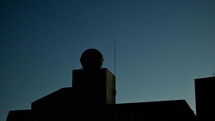 ビル屋上の貯水槽タンクと夜明けの空
