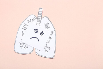 Drawn paper lungs and note with sad face on beige background