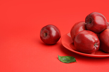 Plate with fresh red apples on color background