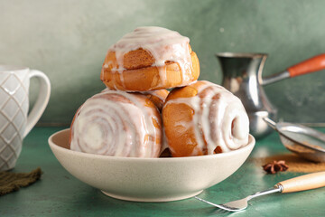 Plate with glazed cinnamon buns, cup of coffee and cezve on green grunge background