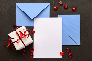 Envelopes with blank card, gift box and hearts on black grunge background. Valentine's Day celebration