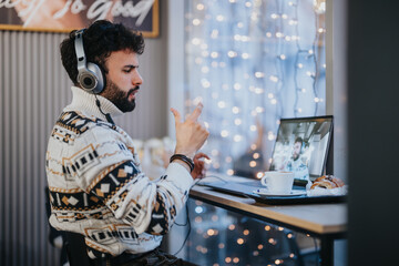 Fototapeta na wymiar A young man wearing headphones participates in an animated online business meeting from his home workspace adorned with twinkling lights.