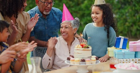 Senior woman, birthday cake and family in garden with applause, celebration and happy together for party. Man, women and children in grandparents backyard with present, dessert and love in summer