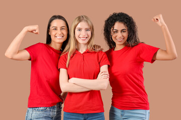 Beautiful young women showing muscles on beige background. Women history month