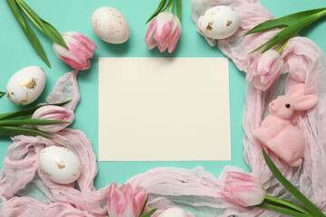 Blank card with Easter eggs, bunny figurine and tulips on turquoise background